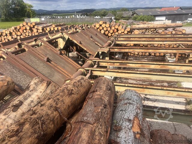 Podawanie drewna okrągłego z piłą przesuwną i skrzynią na odpady. Springer Springer