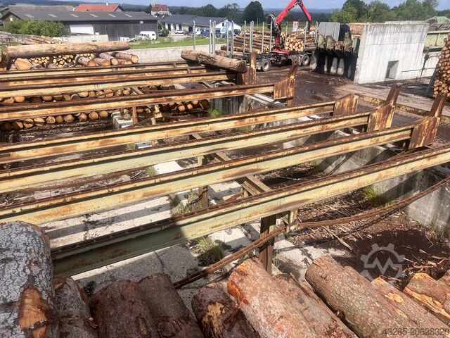 Podawanie drewna okrągłego z piłą przesuwną i skrzynią na odpady. Springer Springer