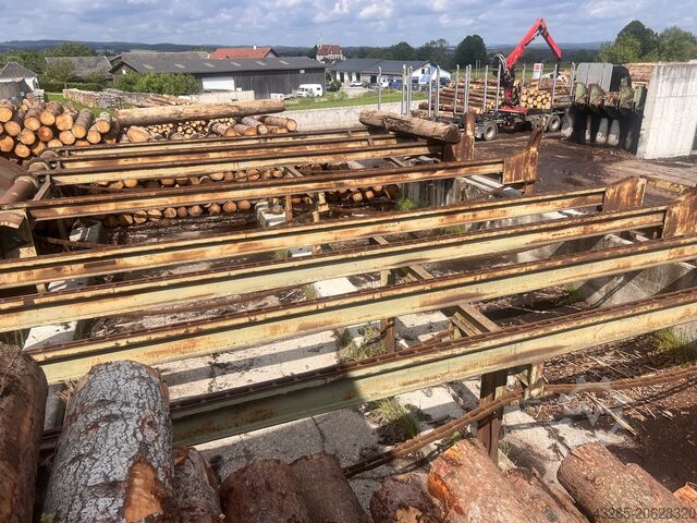 Podawanie drewna okrągłego z piłą przesuwną i skrzynią na odpady. Springer Springer